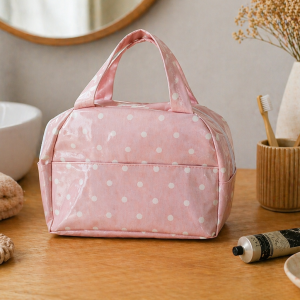 Trousse de toilette femme rose à pois blancs en coton enduit posée sur meuble de salle de bain